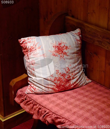 Image of Red pillow kept on a wooden bench