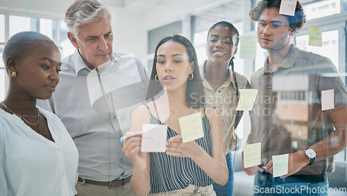 Image of Innovation, meeting or woman writing on a sticky note planning a startup project on glass board in office building. Focus, leadership or creative business people working on strategy ideas or solution