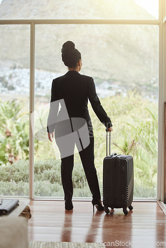 Image of Travel, luggage and glass with a business black woman standing in a hotel looking at the view. Corporate, window and accommodation with a female employee in a luxury or modern apartment for work