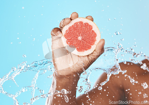 Image of Water splash, grapefruit in hand and studio background for healthy, vegan and nutrition food on advertising, marketing or promotion mockup. African, shower and juice fruit benefits in clean skincare