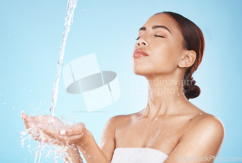 Image of Skincare, beauty and woman with water in hands for luxury facial cleaning and morning routine in studio. Water splash, spa product placement and relax, black woman with skin care on blue background.