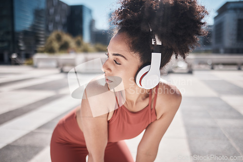 Image of Black woman, fitness and listening to music in the city on a break from running exercise or workout. African American woman runner with headphones for sports training or audio track in the outdoors