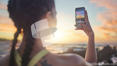 Image of Beach, phone and woman taking photo of sunset for social media during evening workout in Bali. Nature, ocean and fitness influencer with picture of sun in blue sky on smartphone screen in Indonesia.