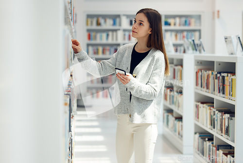 Image of Library, book choice and student with phone in university, college or school. Learning, education scholarship or woman holding mobile looking for books by bookshelf for reading, knowledge or studying