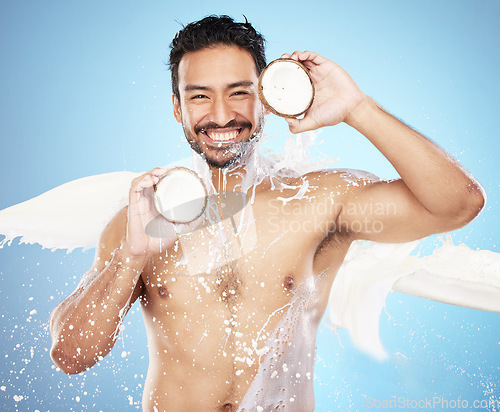 Image of Skincare man, studio and coconut in portrait for milk, splash or smile for body, face or wellness. Model, tropical and fruit for natural cosmetic moisturizer, aesthetic or skin beauty by background