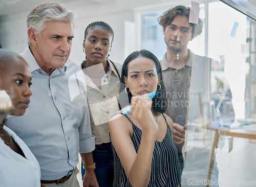 Image of Innovation, meeting or woman writing on a sticky note planning a startup project on glass board in office building. Focus, leadership or creative business people working on strategy ideas or solution