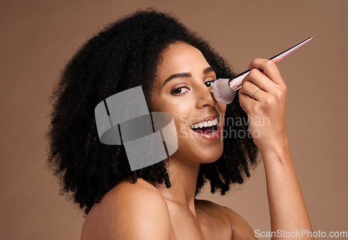 Image of Black woman, studio portrait and makeup brush for foundation, beauty and cosmetic self care by backdrop. Model, happy and powder on nose, face and smile for skincare glow by brown studio background