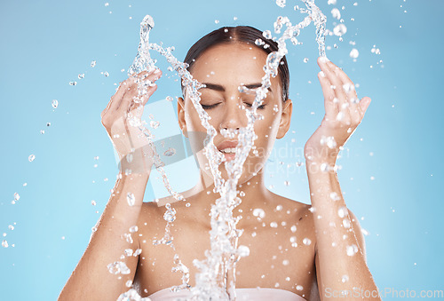 Image of Woman, skincare or washing face with water splash on blue background studio for healthcare wellness, hygiene maintenance or bathroom grooming. Beauty model, hands or facial cleaning with water drops