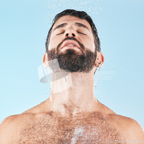 Image of Man in shower, water and clean body with hygiene, grooming and skincare against blue studio background. Cleaning face, model with water drops and facial, natural treatment and cosmetic mockup