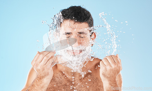 Image of Man, shave and face with water splash in studio for wellness, health and self care by blue background. Model, bathroom and smile with splash for facial beauty, skin product and cosmetics by backdrop