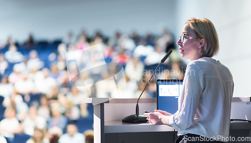 Image of Female speaker giving a talk on corporate business conference. Unrecognizable people in audience at conference hall. Business and Entrepreneurship event.