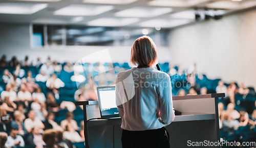 Image of Female speaker giving a talk on corporate business conference. Unrecognizable people in audience at conference hall. Business and Entrepreneurship event.