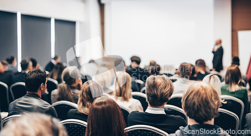 Image of Speaker giving a talk in conference hall at business event. Rear view of unrecognizable people in audience at the conference hall. Business and entrepreneurship concept.