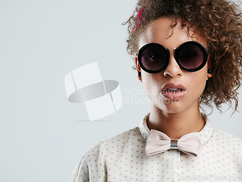 Image of African woman, fashion sunglasses and studio headshot for makeup, beauty or curly hair afro by gray background. Black woman, dark glasses and edgy portrait for bow tie, trendy aesthetic and confident
