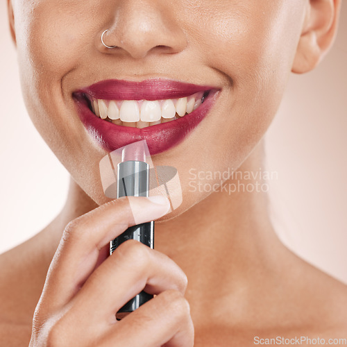 Image of Lipstick, lips and woman with face and beauty, makeup with cosmetics closeup, teeth and dental against studio background. Cosmetic care, product and facial with smile, hand and skincare wellness