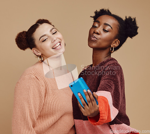 Image of Selfie, friends and women with smartphone, social media and connection on brown studio background. Females, girls and cellphone to share photos, posting and bonding together casual, trendy and smile