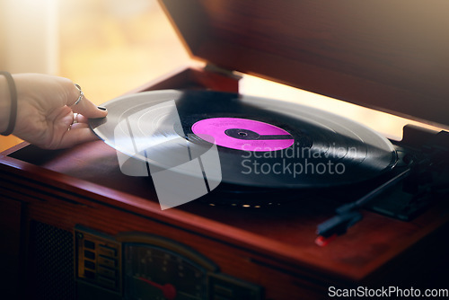 Image of Record player, hand and woman playing music in home living room. Classic technology, retro and female putting vintage vinyl record in turntable or gramophone to play sound, audio or song in house.