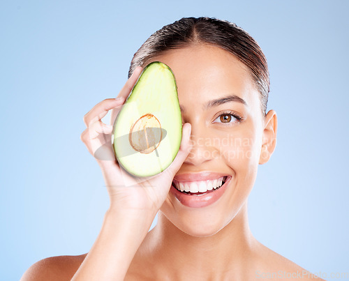 Image of Woman, studio portrait and avocado skincare with smile, health or wellness by blue background. Model, fruit and face with natural cosmetic beauty, glow or healthy aesthetic with self care by backdrop