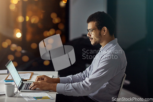 Image of Businessman, laptop and typing with smile for research, analysis or web design on desk at the office. Employee man sitting and working on computer late at night in dedication to meet project deadline