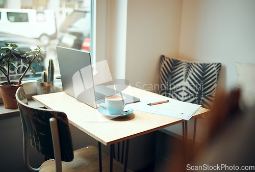 Image of Laptop, documents and coffee shop with a table and chairs in an empty restaurant for freelance or remote work. Business, cafe and coffee with a pen and paper in a workspace at an internet cafe