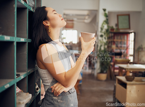 Image of Pottery, coffee and relax with an asian woman taking a break from design in her studio or workshop. Creative, rest and small business with a female artist standing eyes closed in her ceramics startup