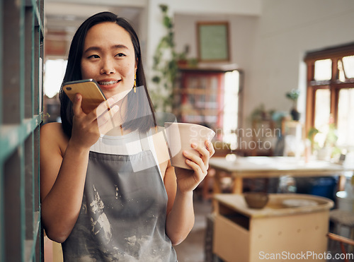 Image of Pottery, phone call and coffee with an asian woman recording a vote note or message in her workshop. Communication, drink and talking with a female designer or artisan in her studio to design