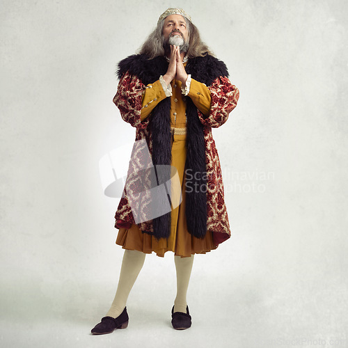 Image of Ancient king man, praying and studio with faith, worship and renaissance fashion by backdrop. Medieval royal leader, clothes and religion with crown, prayer and robe for power, success and gratitude