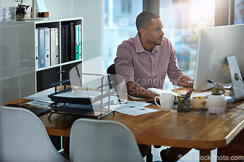 Image of African businessman, office and reading at computer, focus and planning with vision, goal and start morning with ideas. Corporate black man, pc and notebook for strategy, typing or email on internet