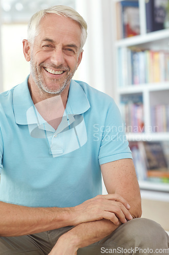 Image of Senior man, smile and portrait of a person in a living room library with happiness at home. House, smiling and relax person sitting by books feeling happy about elderly retirement with wrinkles