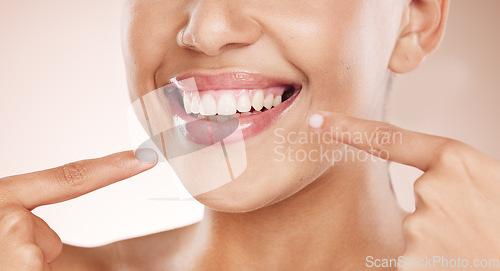 Image of Smile, mouth and woman pointing to teeth on studio background for wellness, aesthetic beauty and healthy cosmetics. Closeup model showing clean dental skin, fresh breath and teeth whitening results