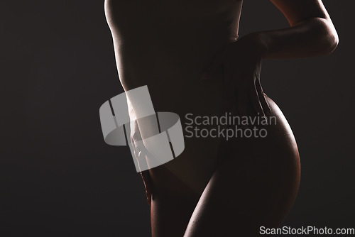 Image of Beauty, body and silhouette of a woman in studio with a sensual, seductive and natural pose. Wellness, body care and shadow figure of a slim girl model posing while isolated by dark black background.