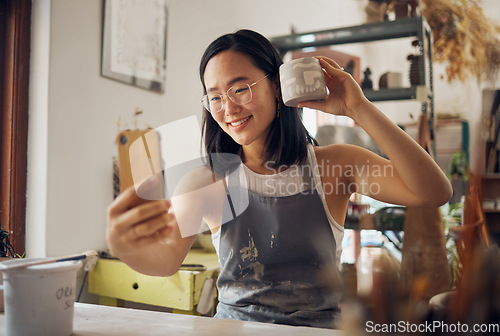 Image of Artist woman, pottery and selfie with smile, design and product in studio to sell on internet, app or social media. Asian art girl, sculpture and smartphone with happiness, vision and artwork at desk