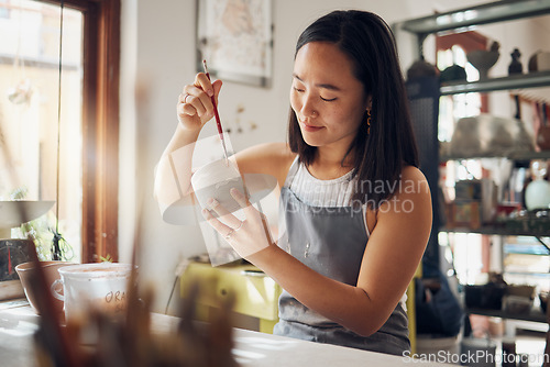 Image of Pottery, art and design with an asian woman in a studio for her creative ceramics hobby as an artisan. Manufacturing, pattern and artist with a female potter sitting in her workshop as a sculptor