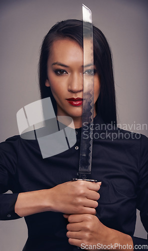 Image of Portrait, sword and warrior with an asian woman in studio on a gray background for martial arts or combat. Training, fantasy and weapon with a ninja or samurai ready to defend using self discipline