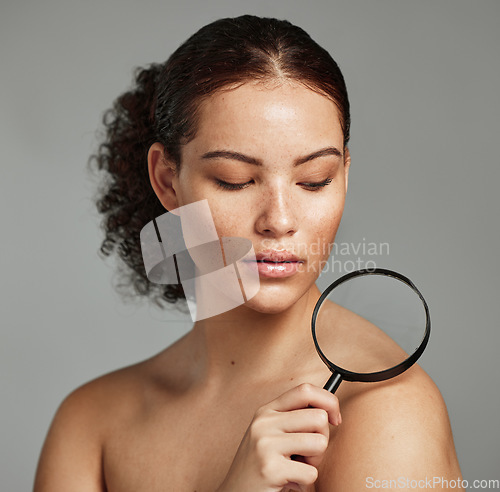 Image of Skincare, magnifying glass and woman in studio for skin, body and wellness against a grey background. Beauty, inspection and girl model relax after grooming, hygiene and cosmetic care while isolated