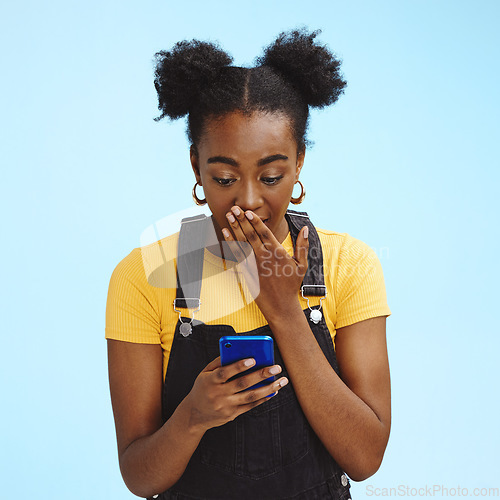 Image of Wow, gossip and shocked black woman isolated on blue background for social media, fake news or post update. Smartphone, surprise notification and people, gen z or person reading text in studio mockup