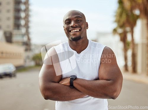 Image of Black man, fitness and smile with arms crossed in the city for running exercise, workout or training in the outdoors. Portrait of a African American, confident and sporty male smiling in a urban town