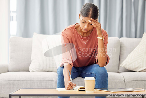 Image of Stress, woman writing and sofa with headache, mental health and debt pressure. Latino female, girl and make notes in book, journal and budget with financial crisis, depression and anxiety in lounge