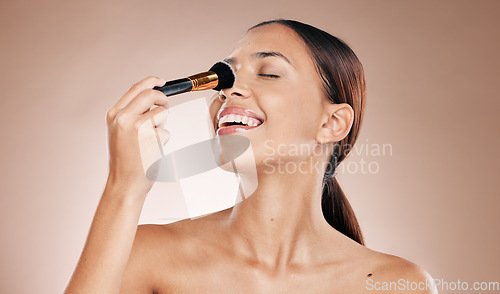 Image of Makeup, brush on face and woman with beauty cosmetics mockup and wellness against studio background. Facial, treatment and cosmetic equipment, smile and foundation application with tools and skincare