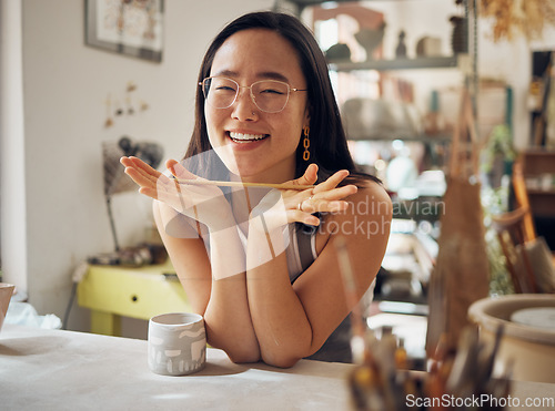 Image of Portrait, pottery and art with an asian woman in her studio or workshop for design and creative hobby. Happy, smile or designer with a female artist working in her small business startup for ceramics