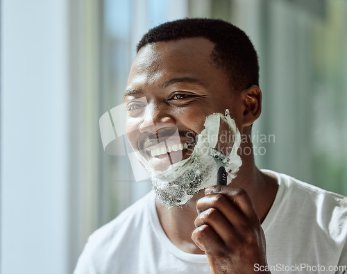 Image of Face, shaving and razor with a black man grooming in the bathroom mirror of his home for beauty or skincare. Beard, shave and blade with a handsome male in the morning for his hair removal routine