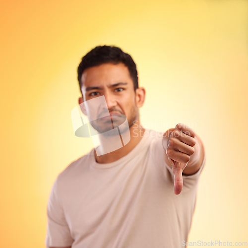 Image of Man, thumbs down and studio portrait with sad, depressed face and frustrated by yellow studio background. Young model, depression or hand sign for emotion, communication and mental health problem