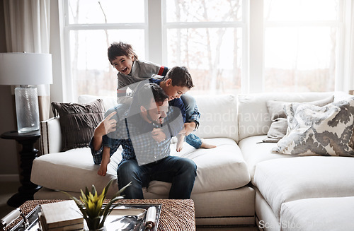 Image of Playful, bonding and father with children on the sofa for playing, quality time and crazy fun. Love, happy and boy kids piling onto their dad with energy on the couch of their family home together