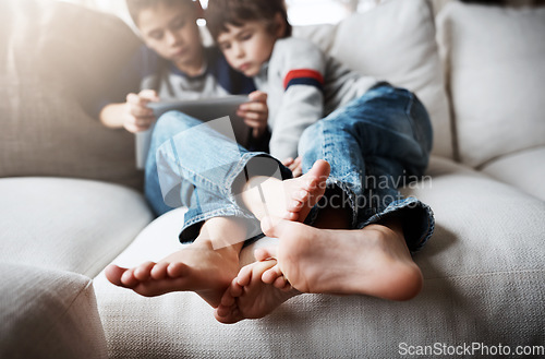 Image of Boy siblings, tablet and sofa to relax with digital app for learning, gaming or web streaming movie. Kids, couch and mobile tech for social media, education or video for development, reading or games