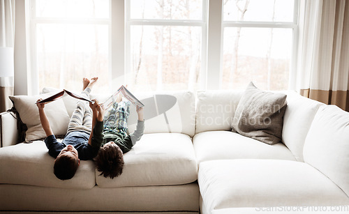 Image of Fun children, bonding and reading books in education, learning or relax studying upside down on house living room or sofa. kids, storytelling and fantasy fairytale novel in creative home inspiration