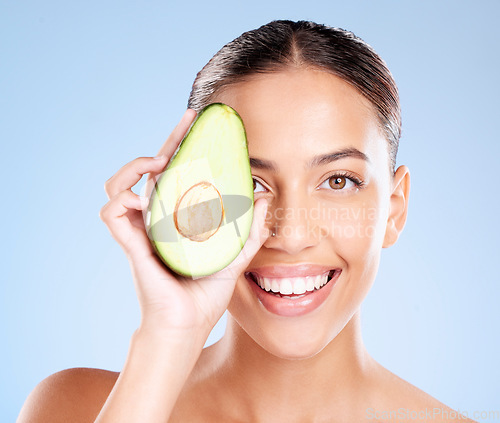 Image of Woman, studio portrait and avocado skincare with smile, health or wellness by blue background. Model, fruit and face with natural cosmetic beauty, glow or healthy aesthetic with self care by backdrop