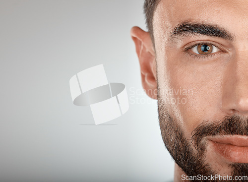 Image of Face, beauty and eye of a man with clean, glow and healthy skin on a grey studio background for dermatology skincare. Portrait of a male with facial cosmetics for self care with marketing free space