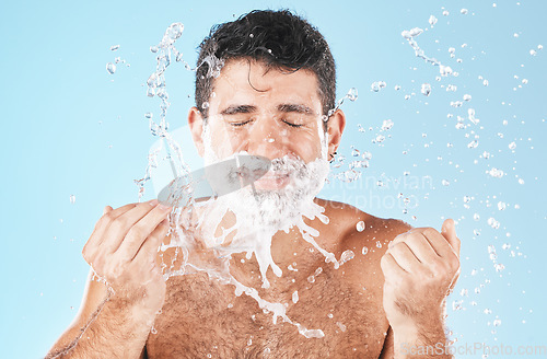 Image of Man, shave and water splash for beauty in studio with wellness, health or self care by blue background. Model, cream and water with hands for healthy facial, self love or cosmetics by studio backdrop