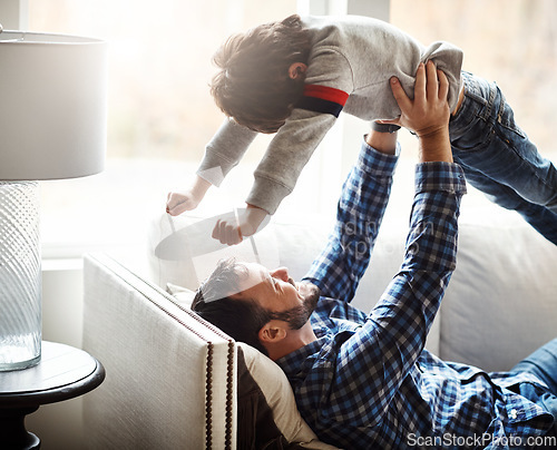 Image of Happy, father and lifting kid on home sofa for bonding, wellness and play together with smile. Dad playing flying in air game with son on living room couch for care, love and bond in family home