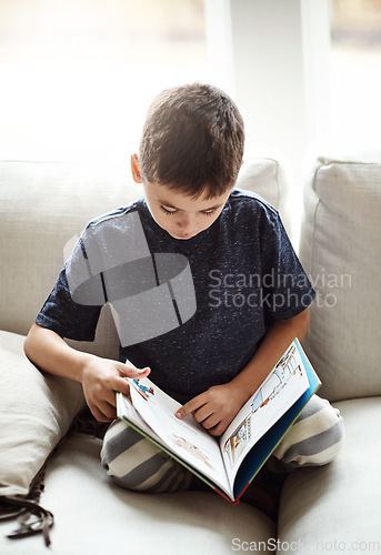 Image of Hobby, boy and reading on sofa, relax and happy on weekend, break and learning. Male child, kid and book for fun, education and story time on couch in living room, happiness and child development